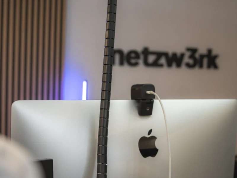 Arbeitsplatz im netzw3rk-Büro mit dem Firmenschriftzug an der Wand